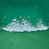 Surfers ride a large wave in the ocean