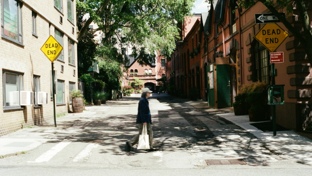 Person walks down a street with "dead end" signs.