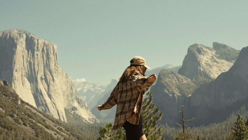 Woman in flannel overlooks yosemite valley mountains