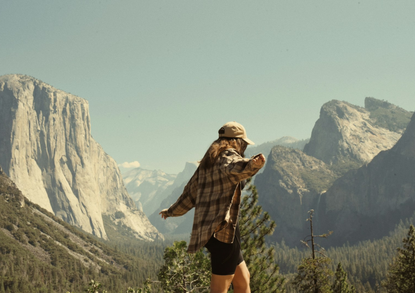 Woman in flannel overlooks yosemite valley mountains